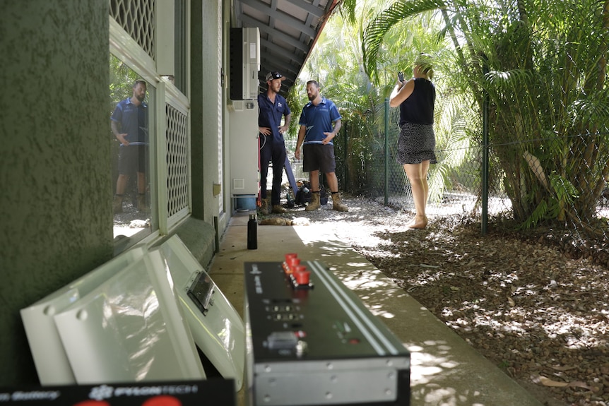 tradesmen next to a house with a battery in the foreground