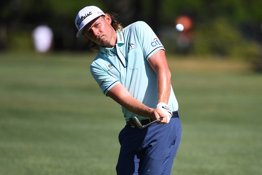 An Australian male golfer watches a shot as he holds an iron at the Australian PGA Championship.