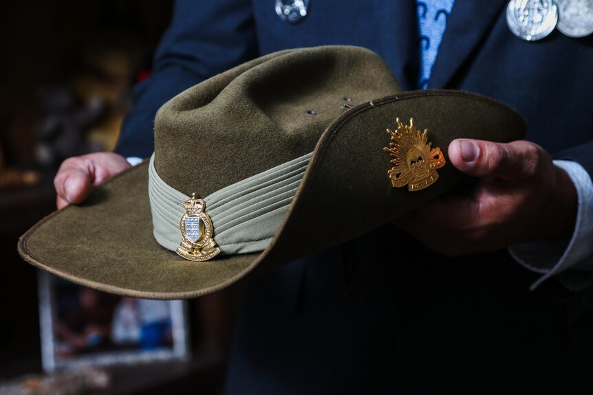 A close up of a pair of hands holding an Australian military slouched hat.