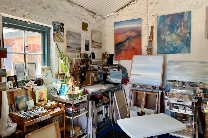 Easels, paints and artworks in a small room 