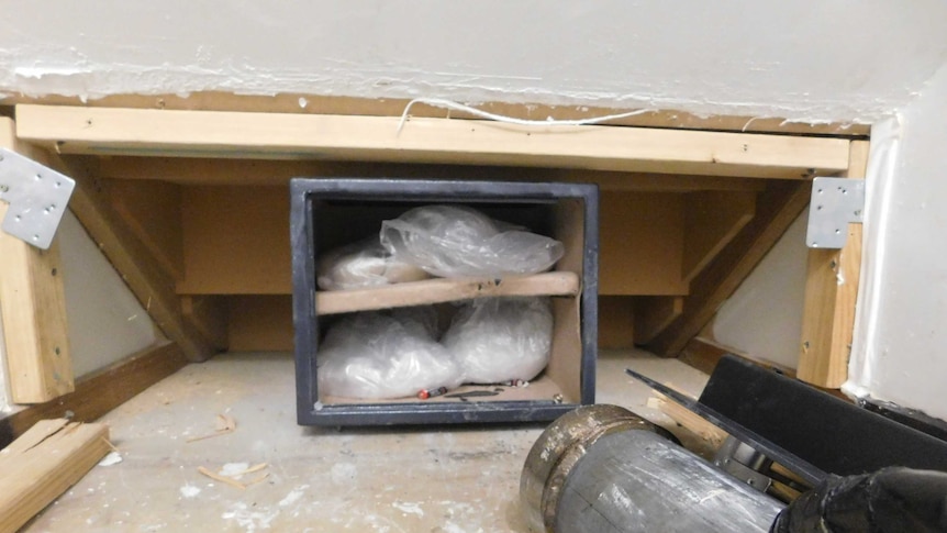 Drugs inside a broken open safe behind a false wall.