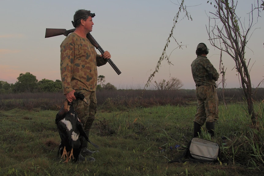 Two hunters at Harrison Dam, one is holding a dead magpie goose.