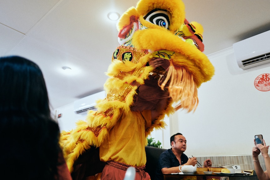 A yellow Chinese dragon dancing through restaurant tables.