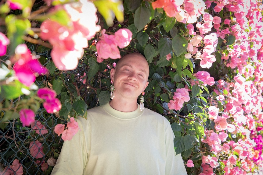 Man smiling surrounded by flowers.