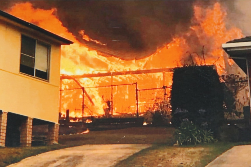 Image of susburban home onfire between two other standing homes.