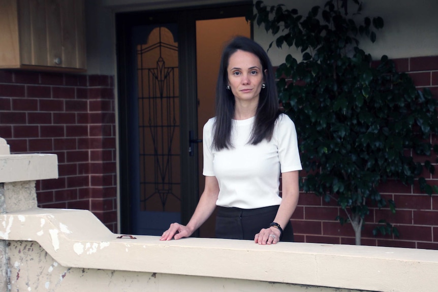 Adele Charalambous stands on the verandah of her house.