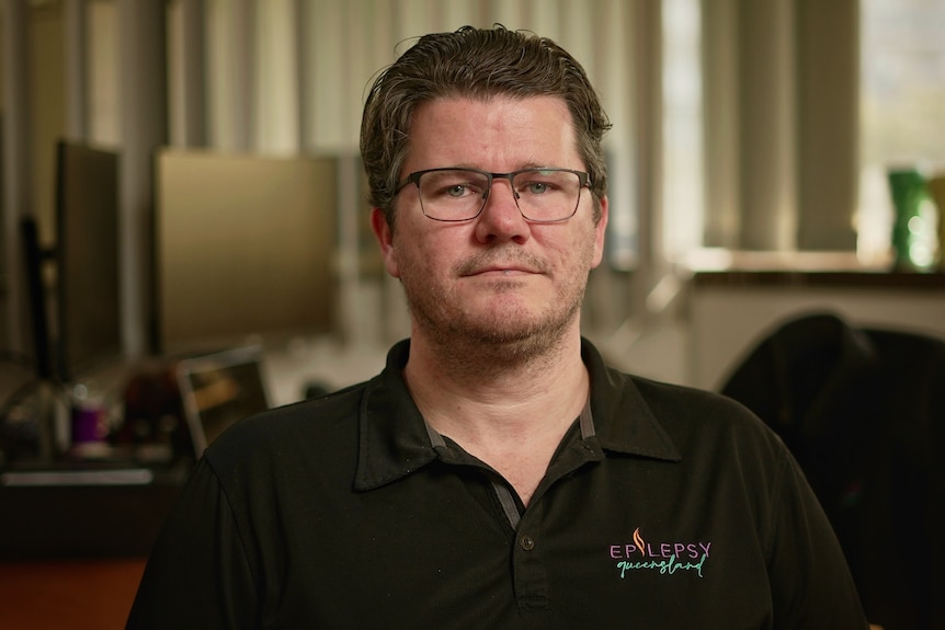 A man in glasses and a black shirt looking at the camera