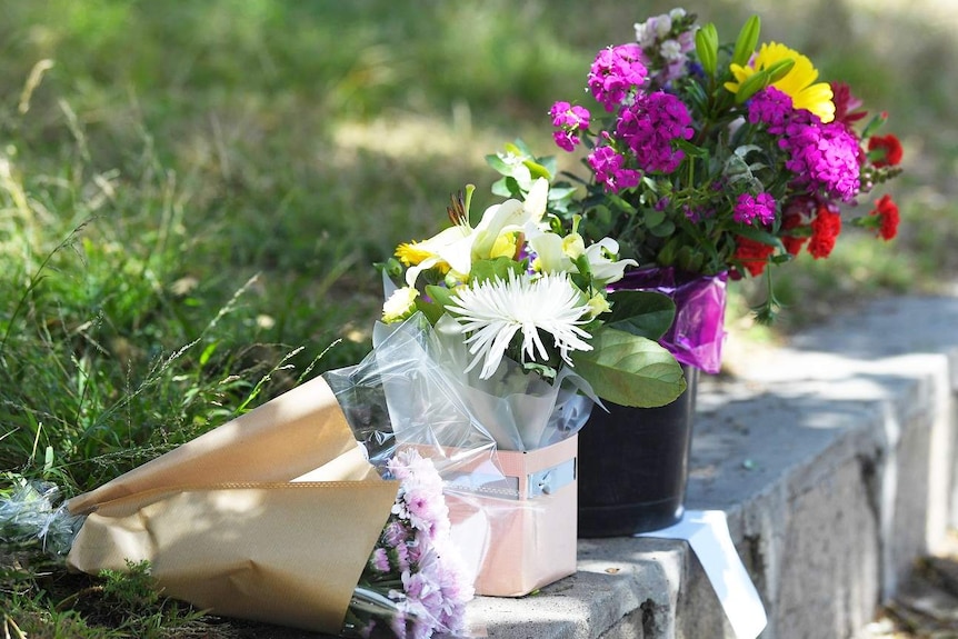 A row of flowers are laid out in a line between a grassy slope and the footpath.