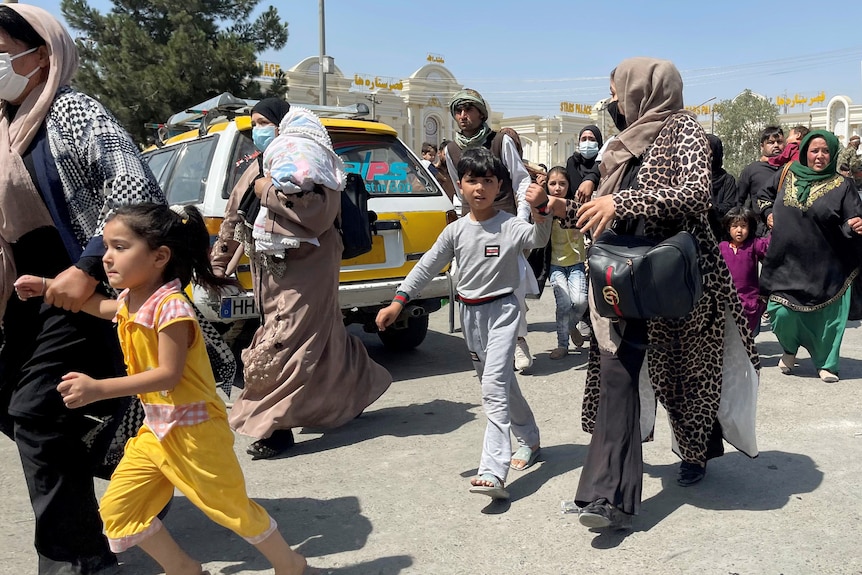 Women and their children flee through a street in Kabul.