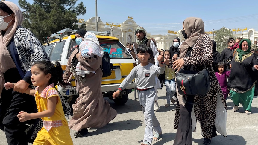 Women and their children flee through a street in Kabul.