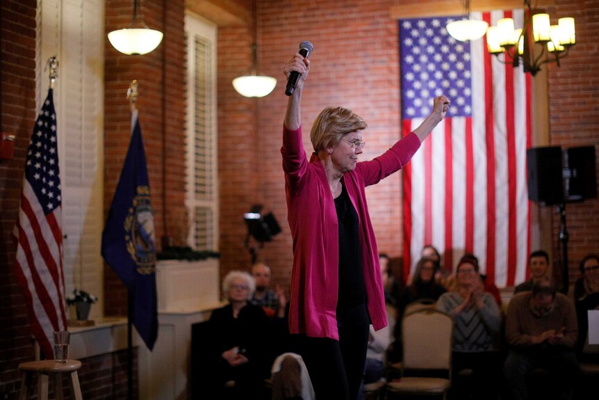 Elizabeth Warren puts both fists in the air as crowds look on.