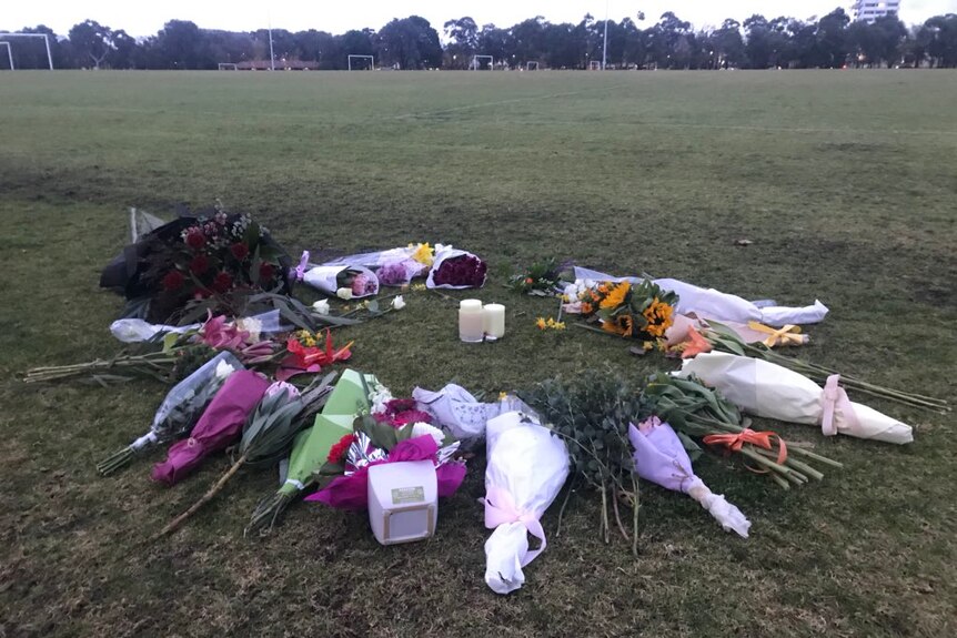 Flowers are placed in a circle around a candle on a soccer pitch at  at Princes Park, where Eurydice Dixon's body was found.