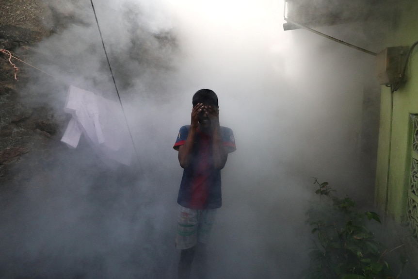 Boy in red shirt in cloud of smoke 