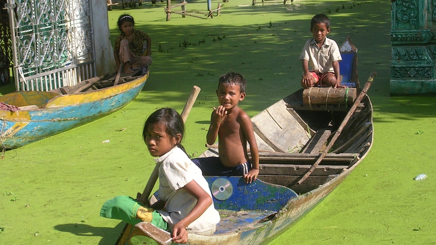 Cambodian children in a boat on floodwaters