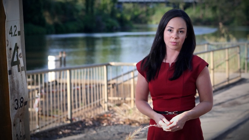 A woman in a red dress with black hair. A river behind.