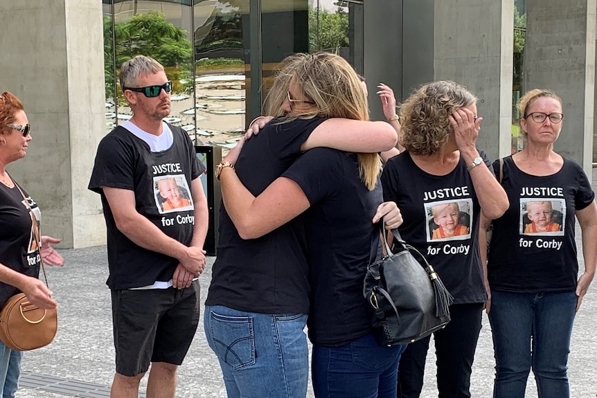 Tanya Jeffrey hugging another family member surrounded by supporters outside court.