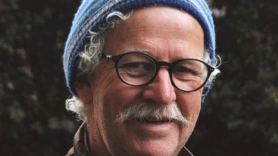 Environmental commentator and author, Andrew Darby wearing a blue striped beanie and glasses.