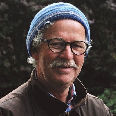 Environmental commentator and author, Andrew Darby wearing a blue striped beanie and glasses.