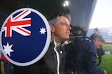 A man sits behind an Australian flag