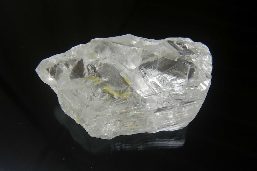 A close up of a 227 carat white diamond on a black background.
