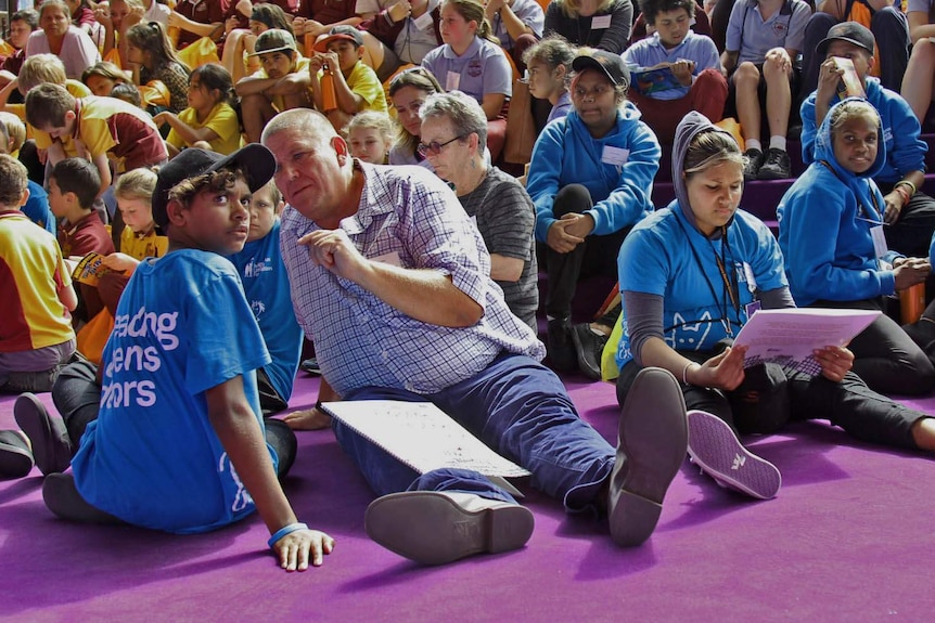 A man and boy speak in a large crowd.