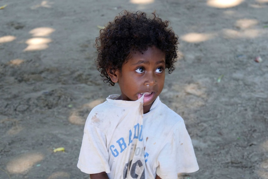 A young boy bites his own shirt in Tulu on Manus Island.
