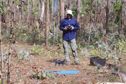 A man in a hat flies a drone