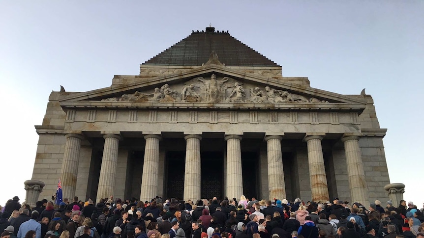 A crowd of young and old people outside a big building in Melbourne for Anzac Day.