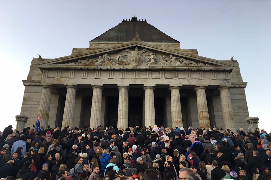 A crowd of young and old people outside a big building in Melbourne for Anzac Day.