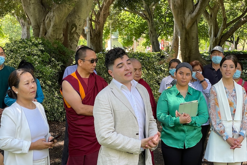 Drew Pavlou speaks with a crowd of people around him at an outdoor event in Sydney. 