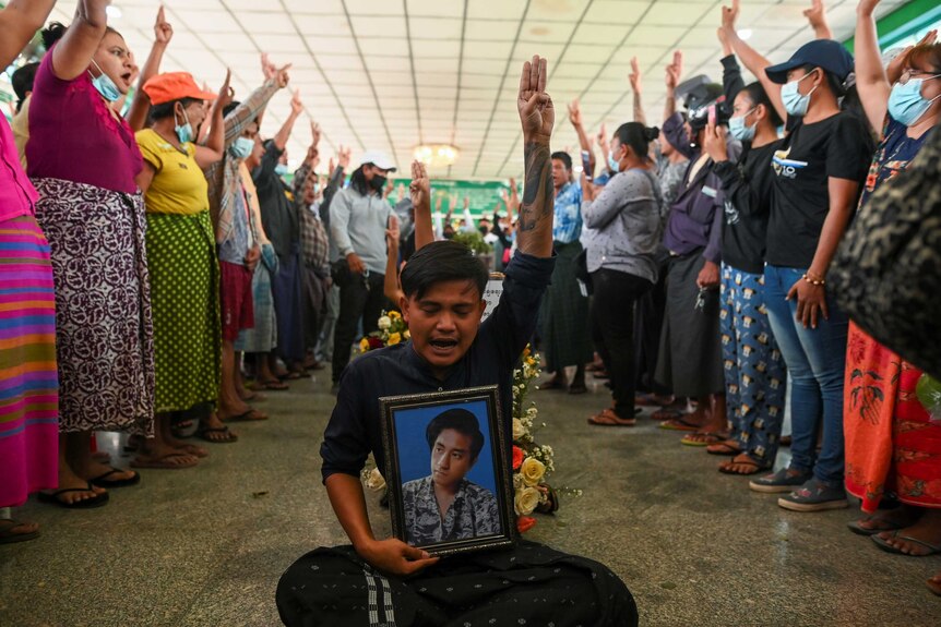People flash a three-finger salute as they attend the funeral of victims shot dead during the anti-coup protest in Yangon.