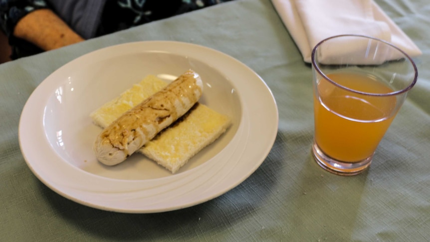 The sausage invented by Lyndoch Living on a piece of bread next to a glass of orange cordial.