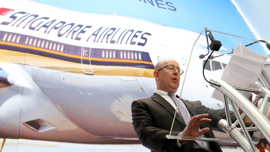 Stephen Byron stands in front of a Singapore Airlines backdrop.