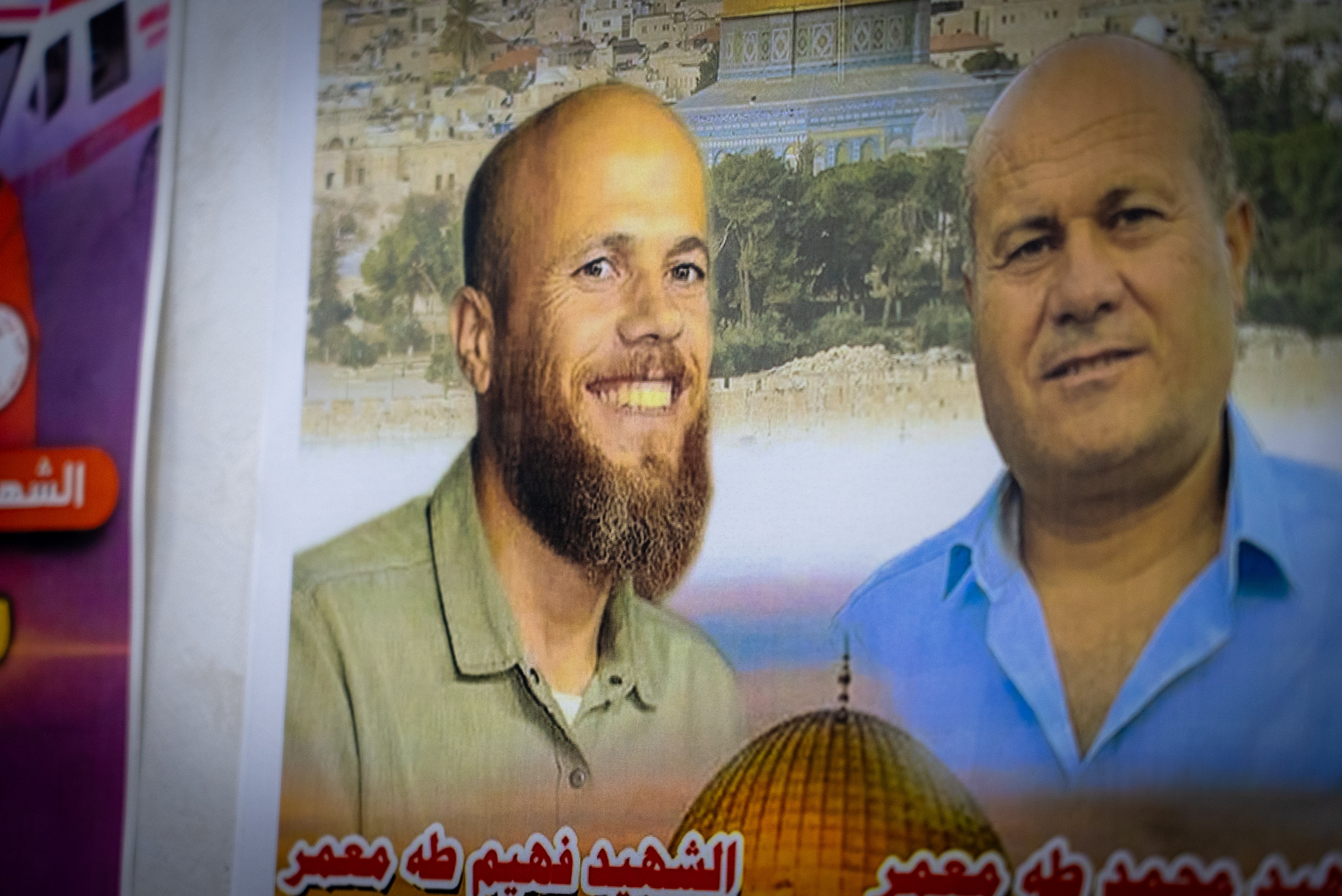 A sign with two Palestinian men is displayed on the wall of an office.