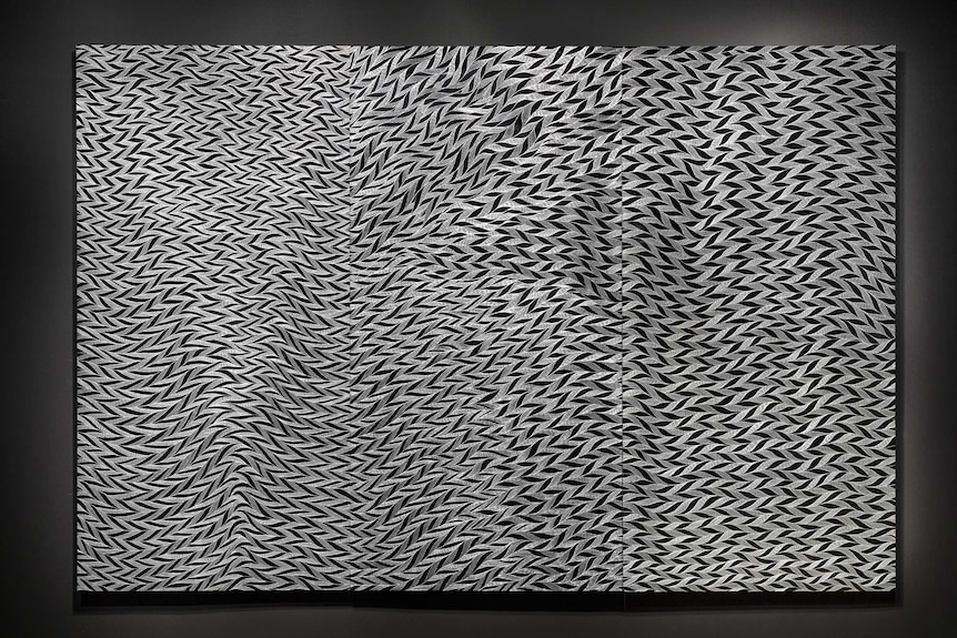 Black wall hung with large three-panel work made from etching on aluminium, in black and silver pattern.