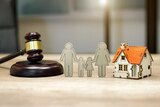 Cardboard cutout of a family surrounded by a doll sized house and a gavel.