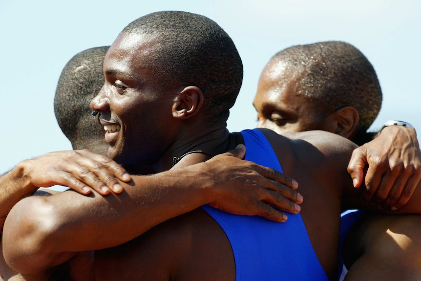 Three athletes embrace.