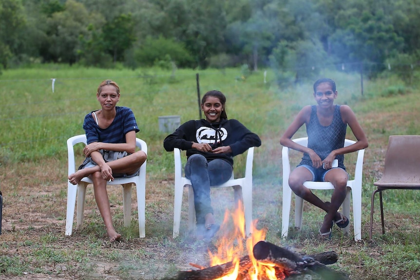 Teenager Zeritta Jessell and her friends sit in plastic chairs around a campfire.