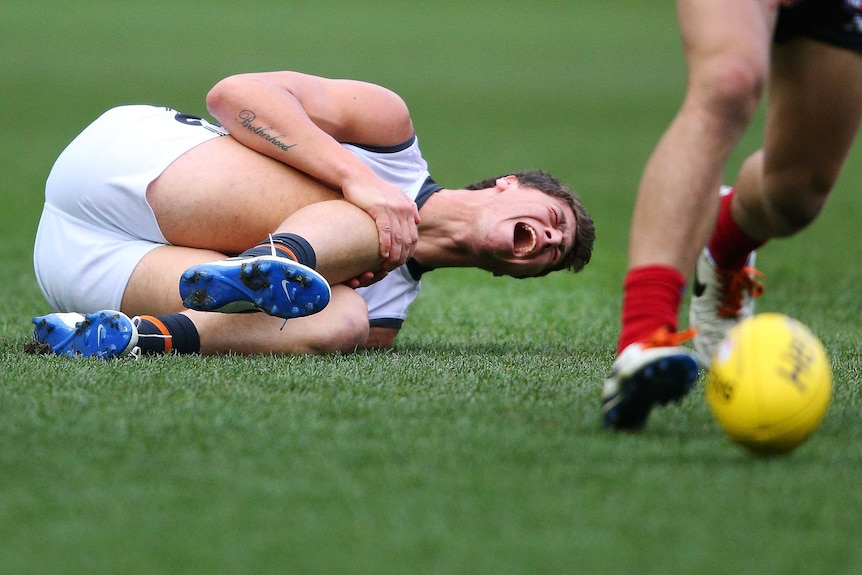The Giants' Jonathon Patton injures his right leg against the Demons in August 2014.