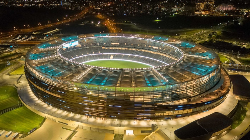 An aerial shot of Perth Stadium lit up at night.