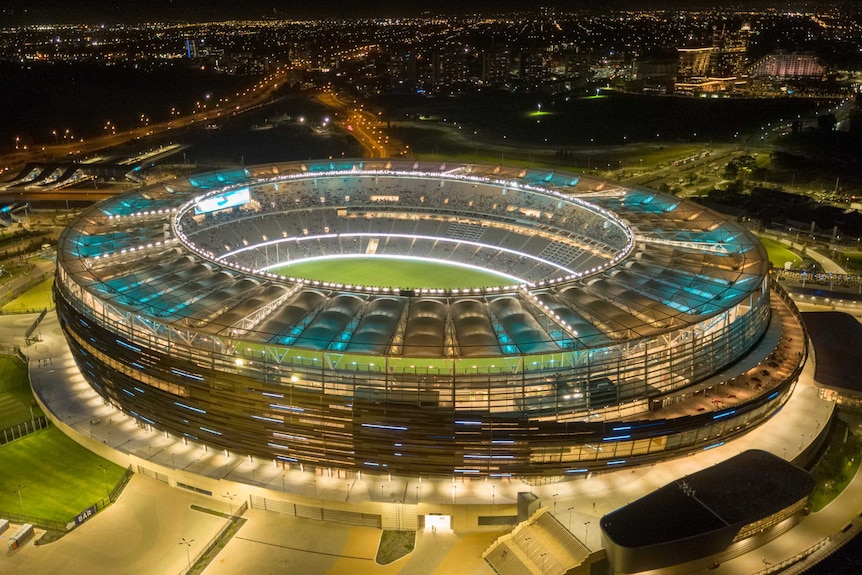 An aerial shot of Perth Stadium lit up at night.