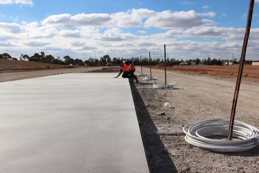 A person laying a large concrete slab.