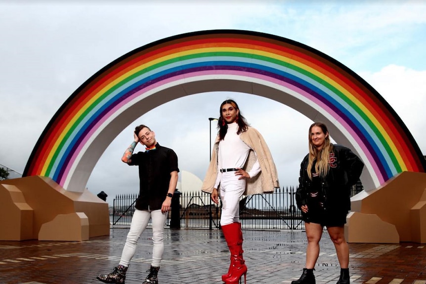 three community ambassadors stand in front of a 14m rainbow