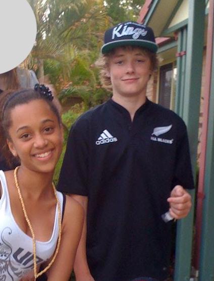 A school-aged girl wearing a white singlet and a boy wearing an All Blacks jersey smile at the camera.