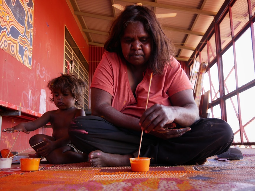 A Balgo woman paints a picture with her child, August 2022. 