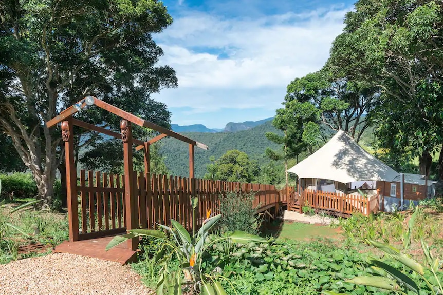 A walkway leading to a tent with a mountain view in the background