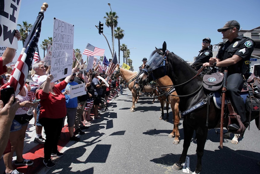 Police officers on horses keep watch over protesters in California.