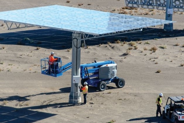 Men in hard hats work around a large solar panel.