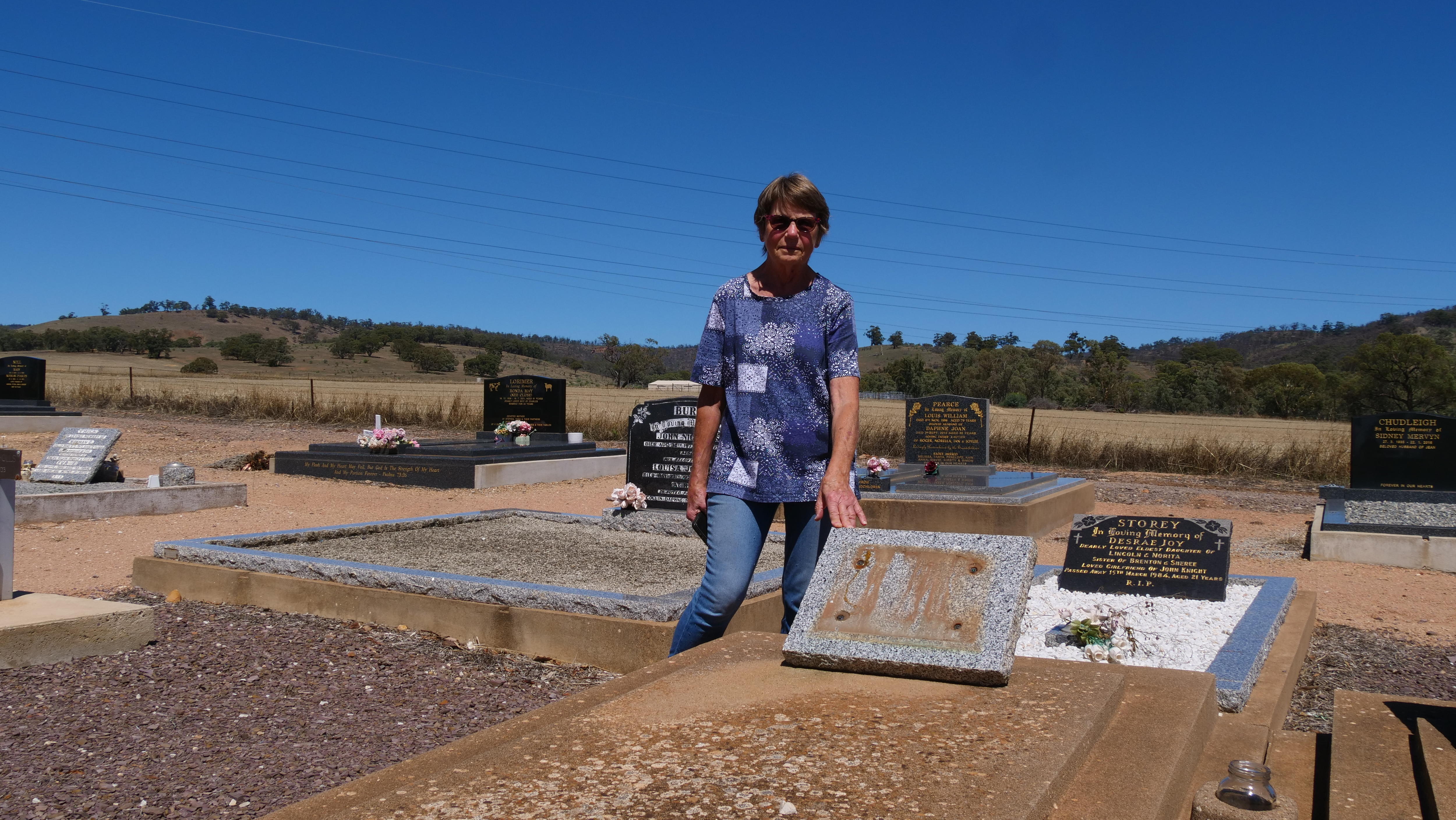 Roslyn Roocke se encuentra detrás de la tumba de cemento donde falta una placa conmemorativa.