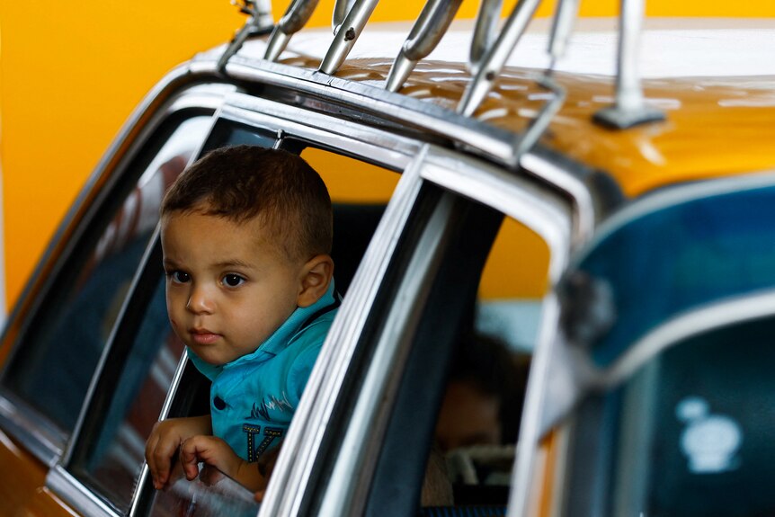 young boy looks out window of taxi